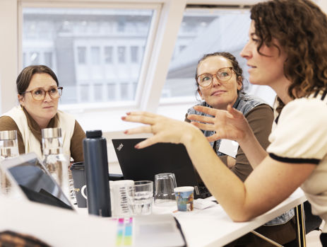 Tre gymnasielærere taler sammen ved et bord