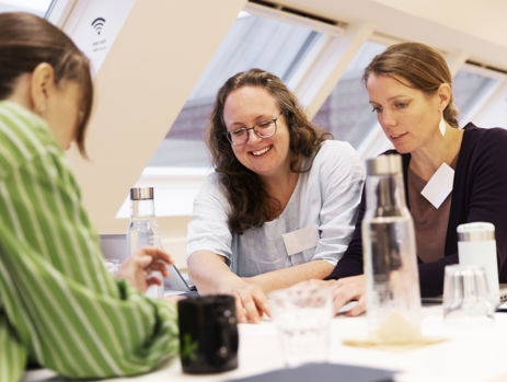 To gymnasielærere samarbejder og griner ved et bord