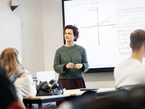 Gymnasielærer underviser klasse foran smartboard