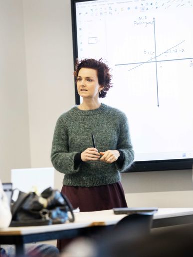 Gymnasielærer underviser klasse foran smartboard